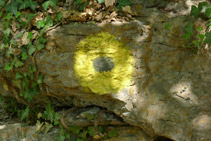 Círculo amarillo que hay pintado en un muro de piedra seca.