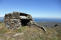 Justo al lado de las antenas hay una cabaña de piedra seca.