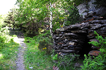 Cabaña de piedra seca dentro del bosque.