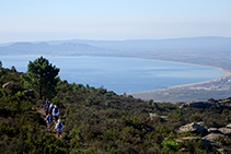 Camino que progresa a media vertiente con la llanura ampurdanesa y el golfo de Rosas al fondo (fuera de ruta).