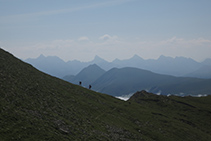 Dos excursionistas subiendo hacia la cima. Al fondo: la Mesa de los Tres Reyes, el Petrechema, el Sobarcal, el Acherito y el Chinebral de Gamueta.