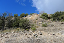 Tramo rocoso coronado por una pared con una arcada de piedra.