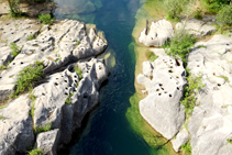 La erosión de las aguas sobre el lecho del río.